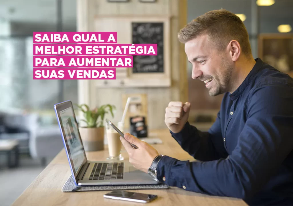 Empresário comemorando sucesso em vendas ao consultar seu smartphone e laptop em um café.