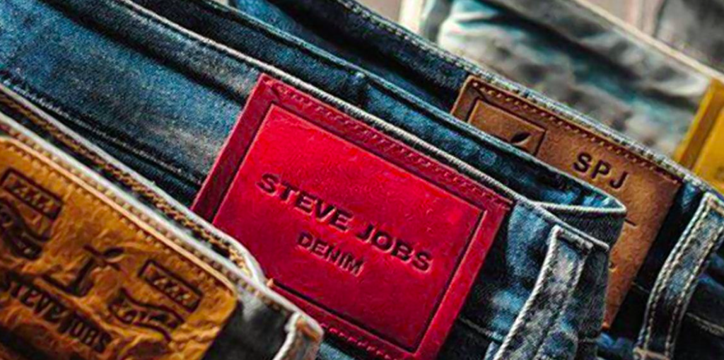 foto com calças jeans e em uma delas consta a etiqueta das marcas escrito Steve Jobs denim